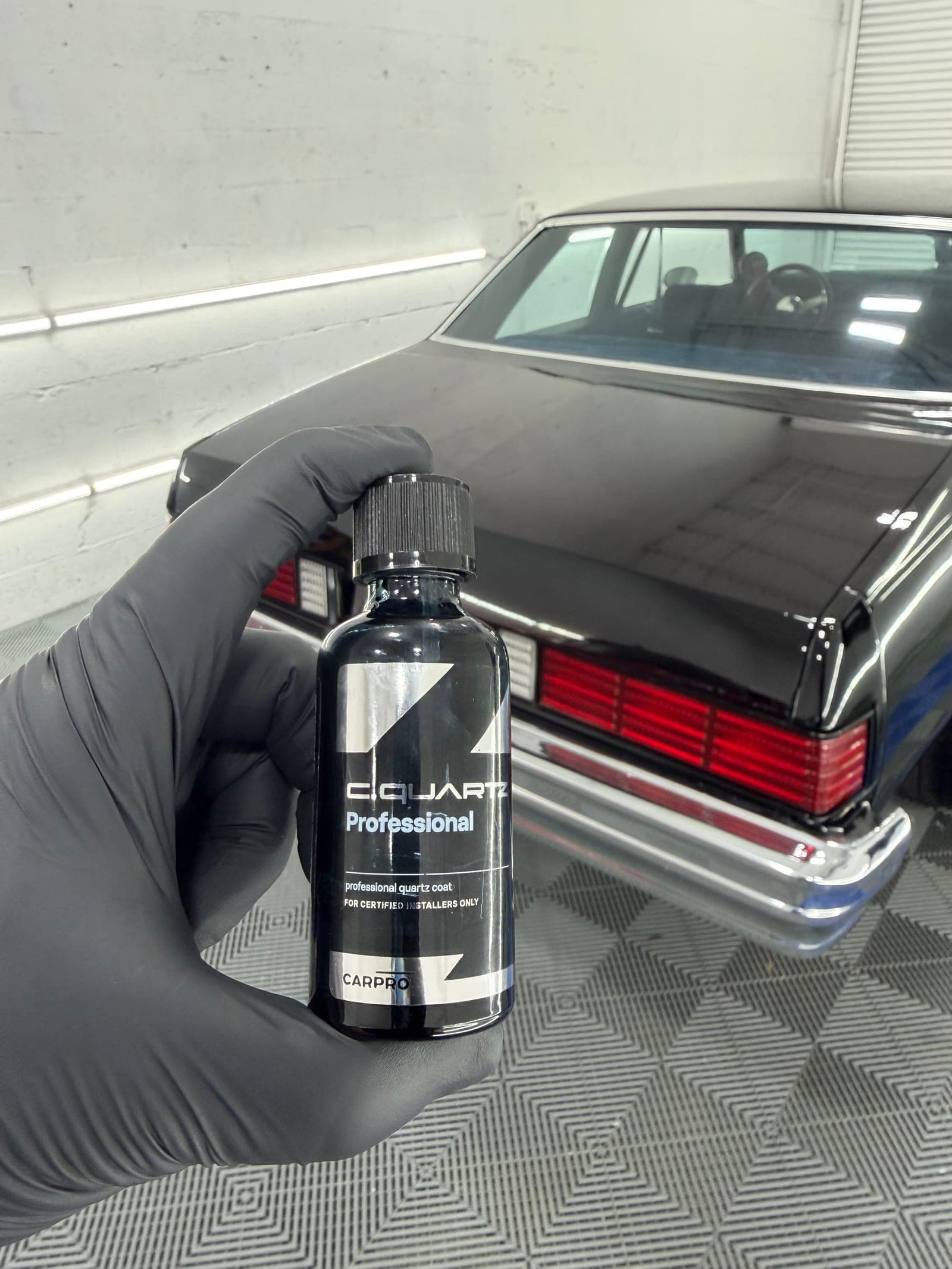 Black sedan under CQuartz ceramic coating — deep wet gloss after cure