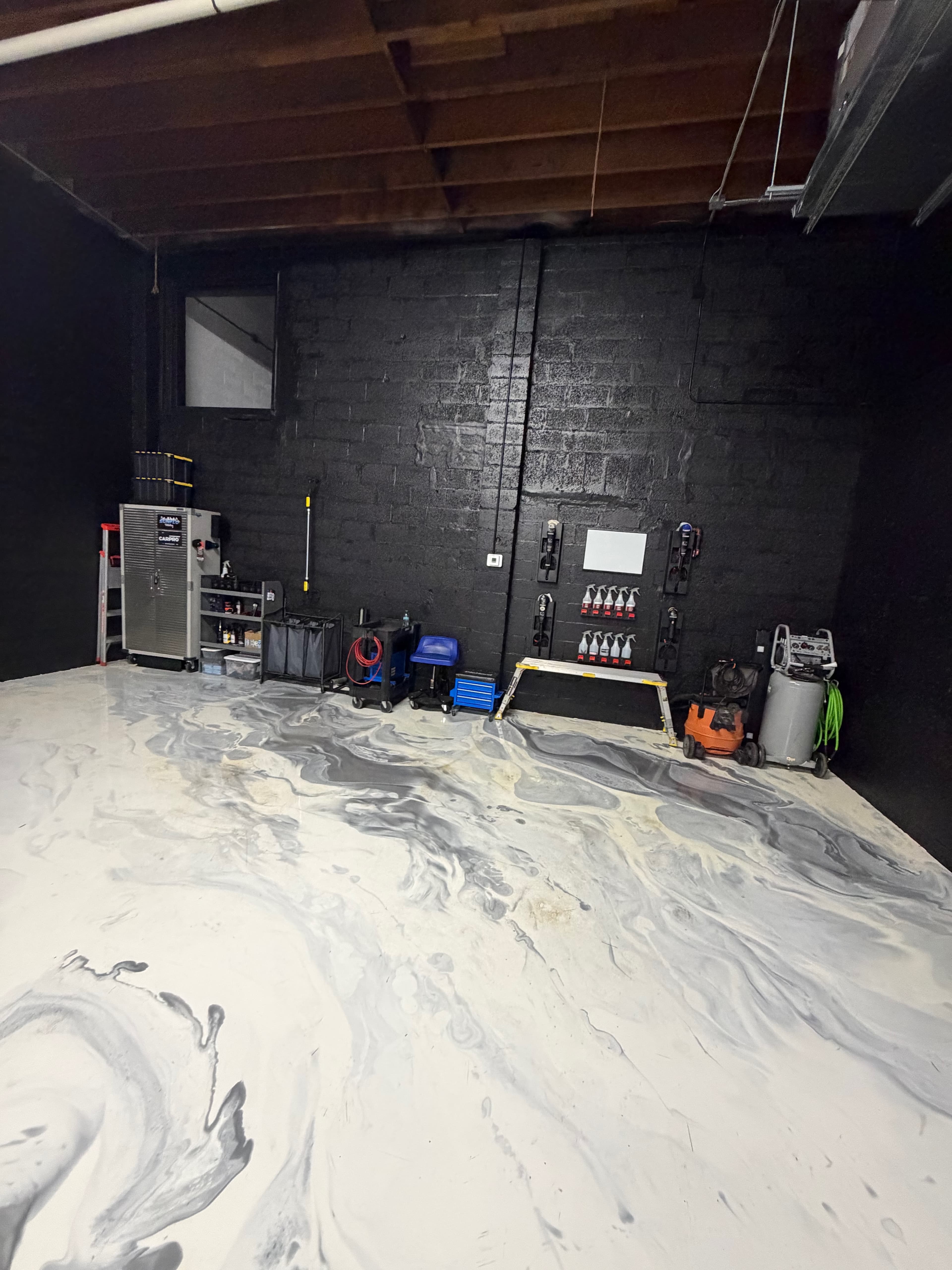 Inside the new Sunflo Detailing studio in Fort Lauderdale — black brick walls, marbled epoxy floor, and tool storage along the back wall