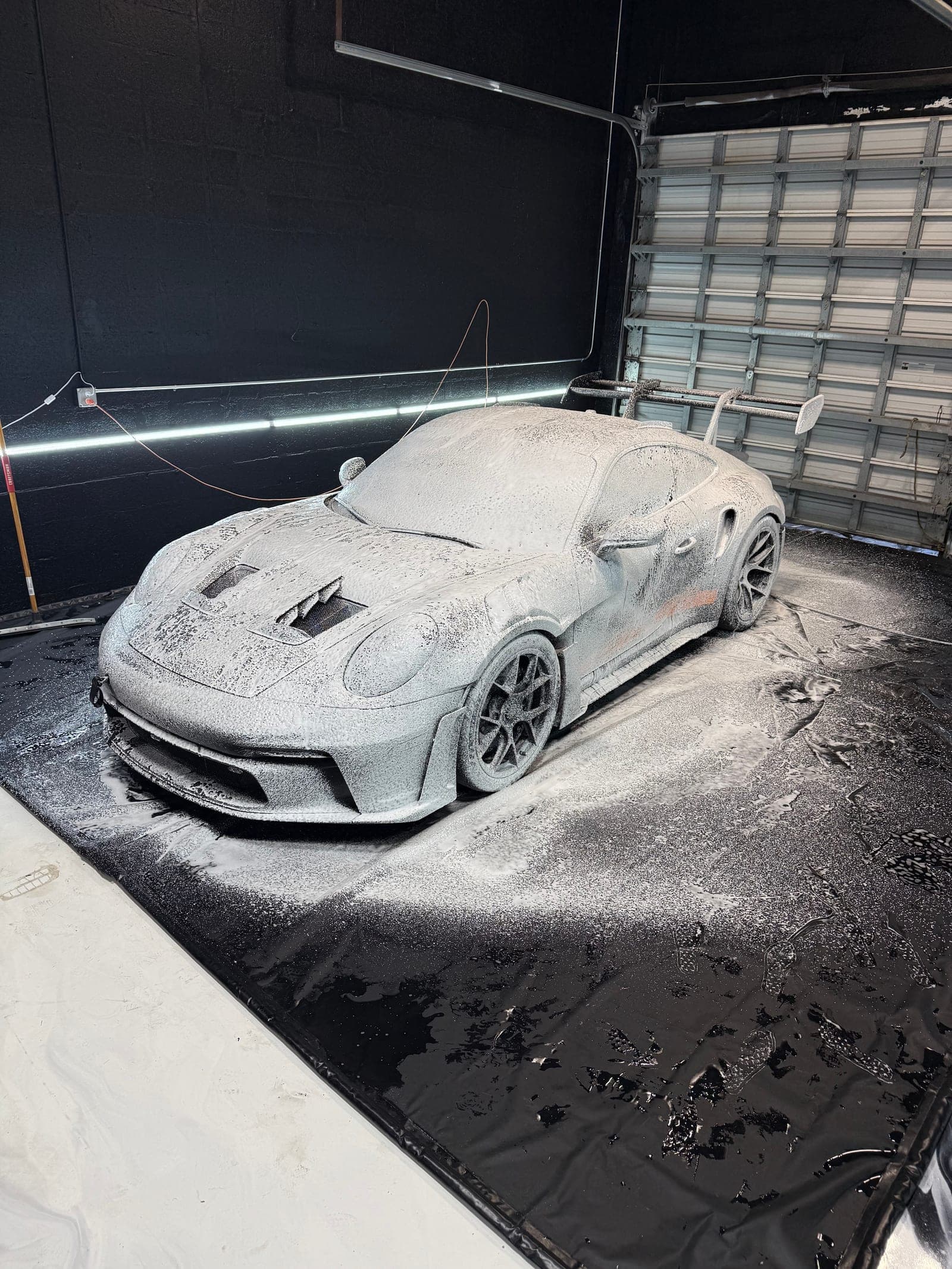 Porsche 911 GT3 blanketed in snow foam during the pre-wash stage of a full detail