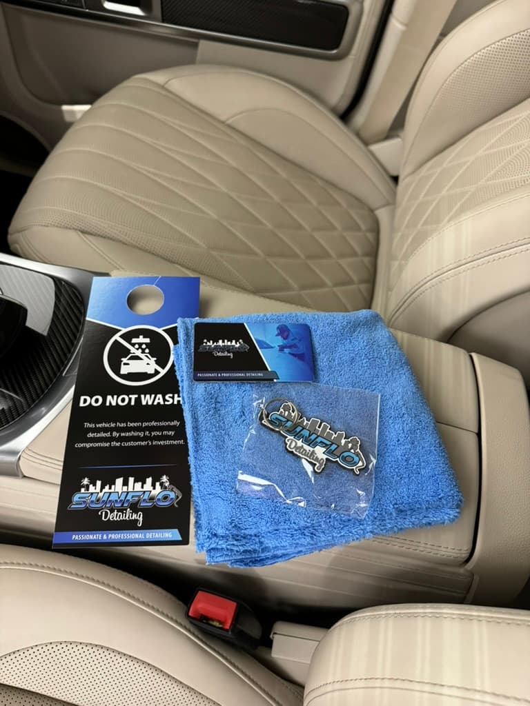 Sunflo detail kit — Do Not Wash tag, business card, microfiber, and logo sticker left in a freshly detailed cabin