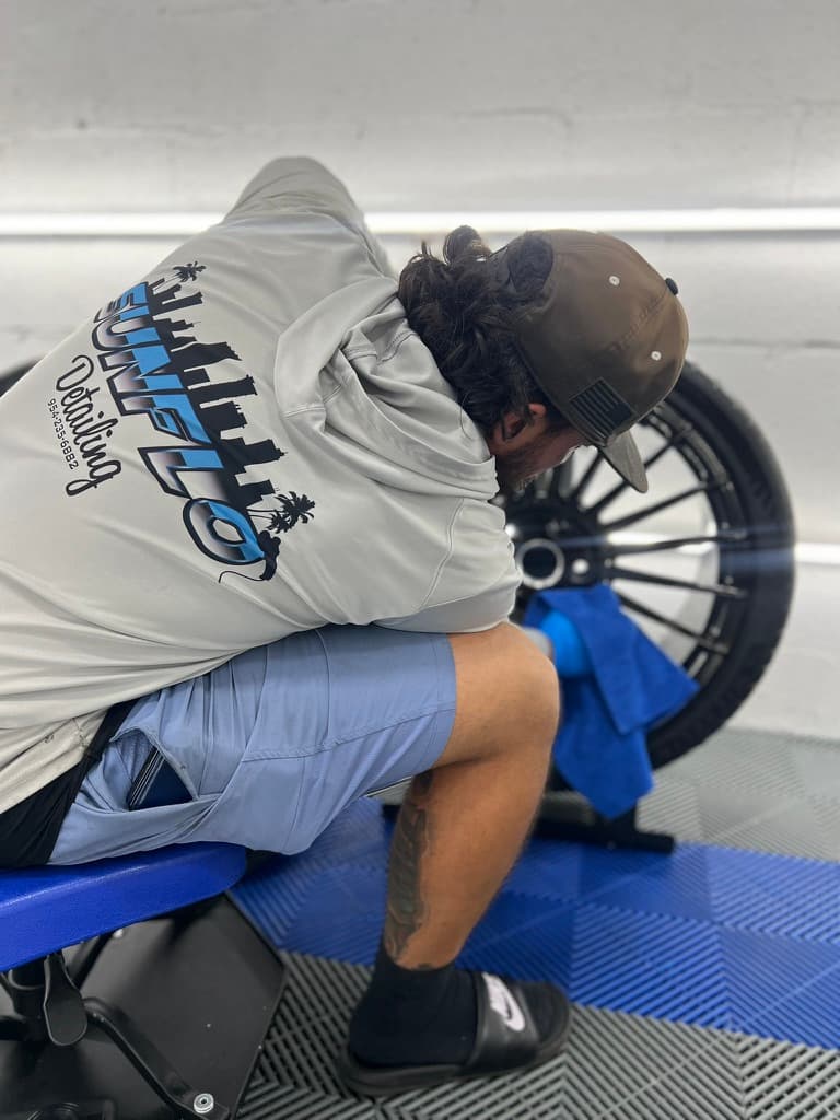 Sunflo tech hand-detailing a motorcycle wheel — every spoke, every surface