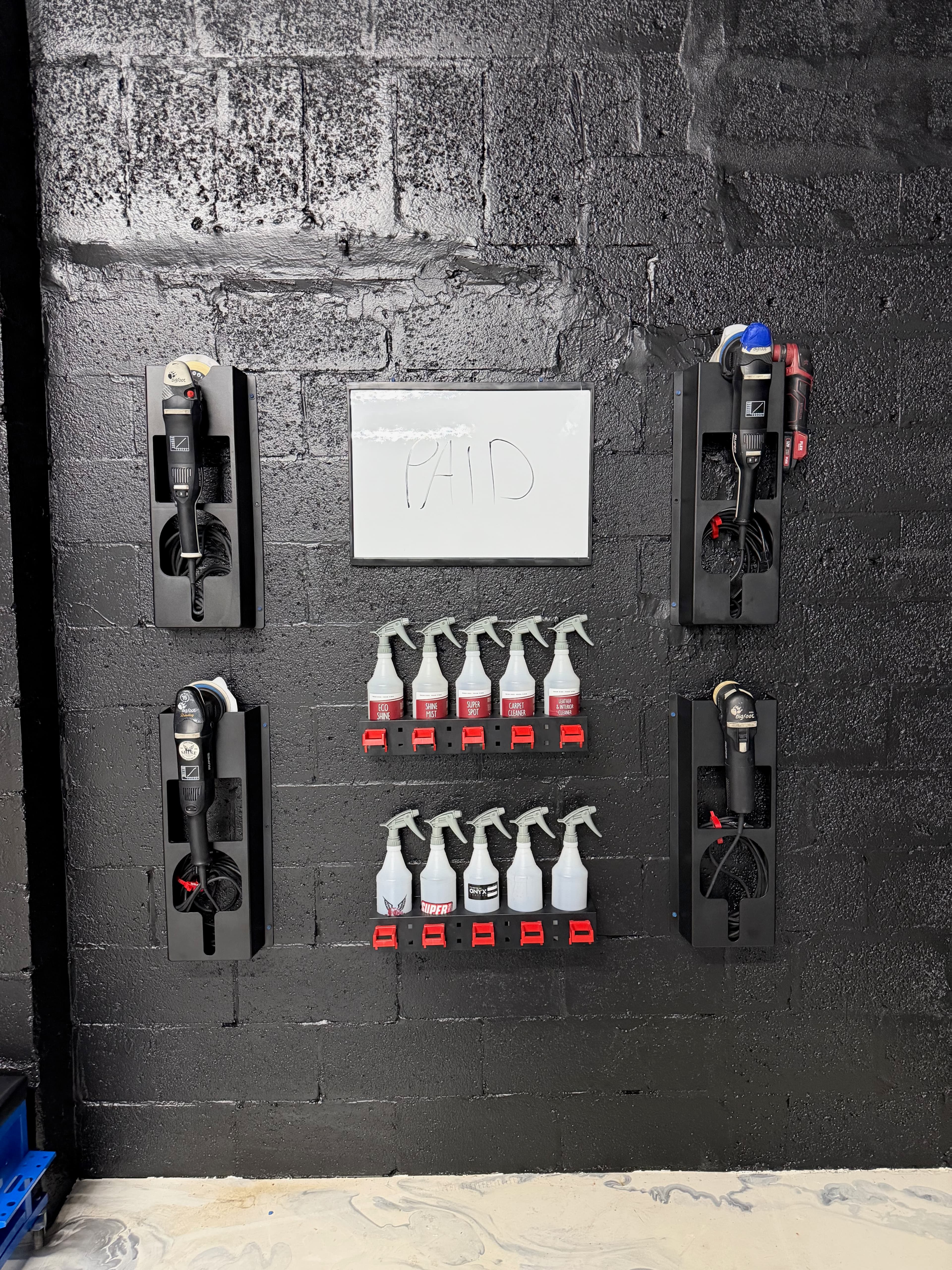 Polisher and chemical storage wall inside the Sunflo Fort Lauderdale studio — mounted machines and labeled spray bottles