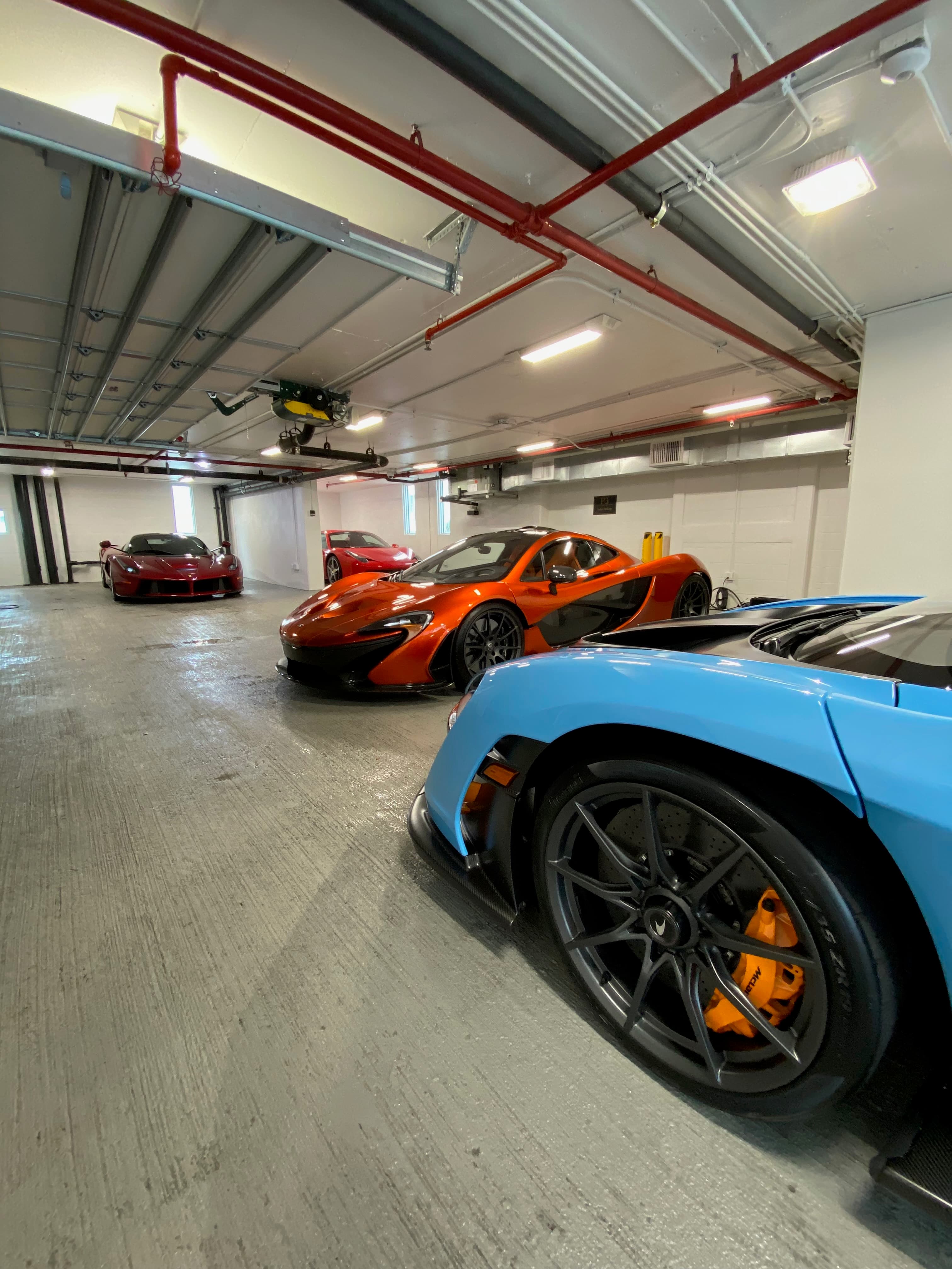 Orange McLaren P1 alongside a Ferrari LaFerrari in private collection storage — paint paint protection clientele