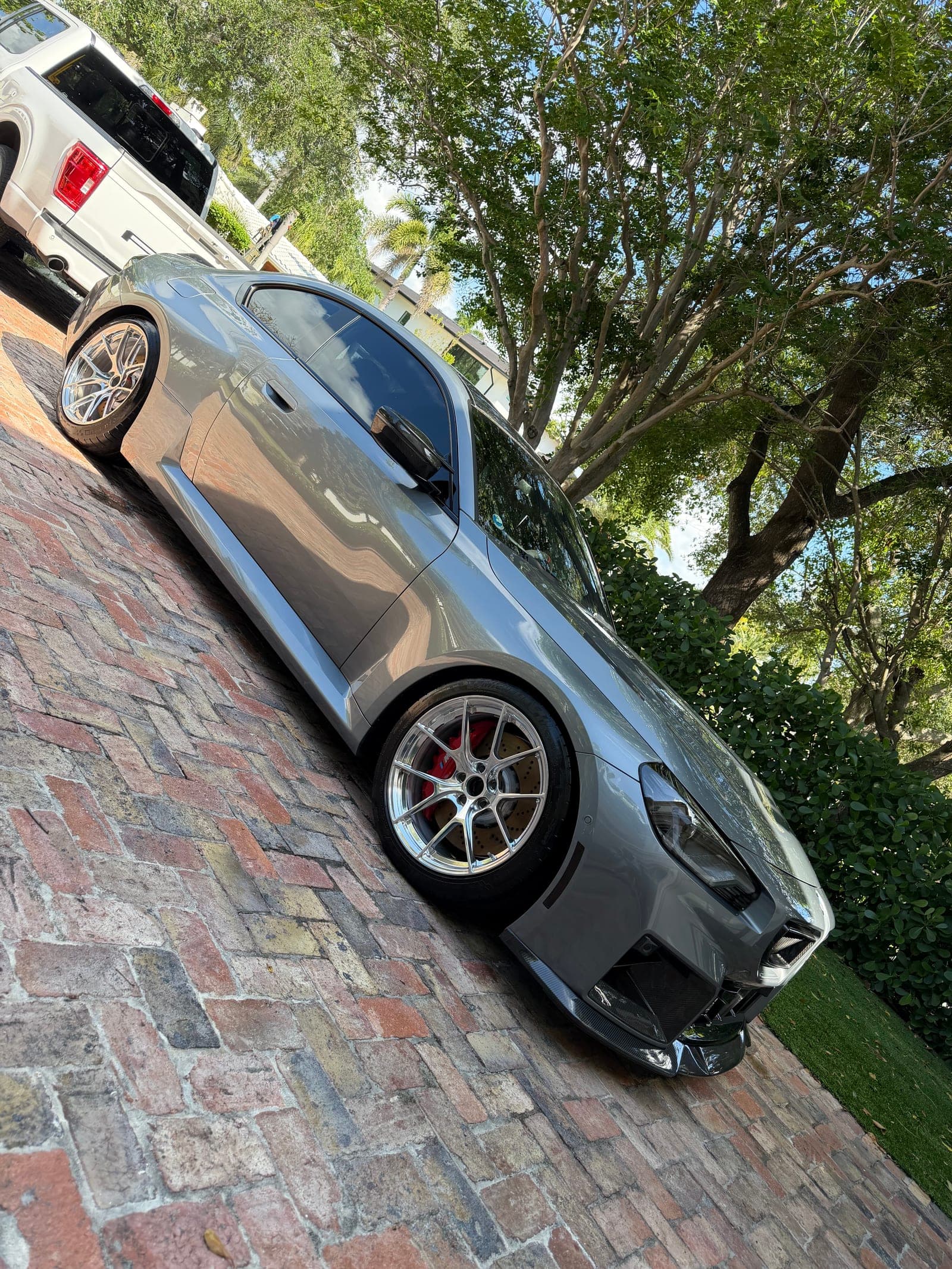 Silver Porsche GT3 on the brick driveway after a full wheel and exterior detail — polished spokes, red calipers